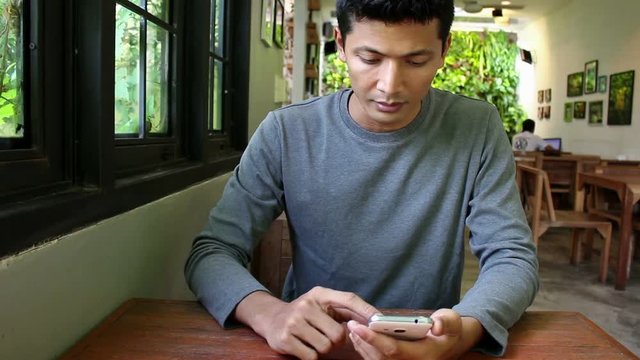Young man using smartphone for relaxing in coffee shop