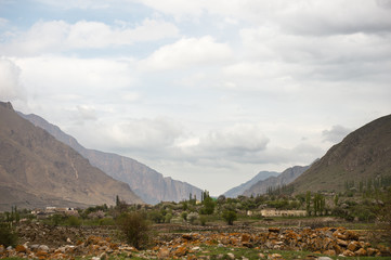Mountain settlement in the Caucasus is located among the mountains in a quiet valley against the background of beautiful clouds