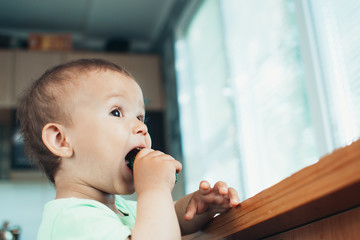 Little boy eating a fresh cucumber