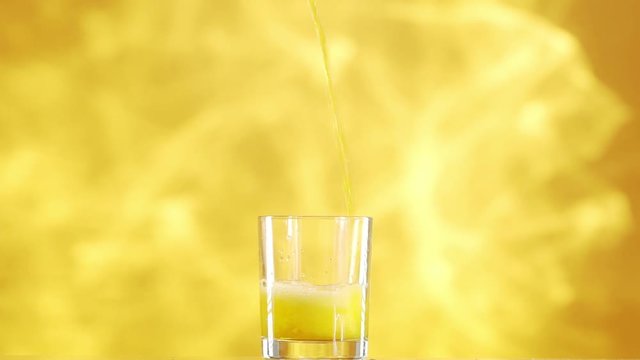 Soda Water Is Pouring Into Old Fashioned Glass Standing On Bright Yellow Smoky Background In Slowmotion