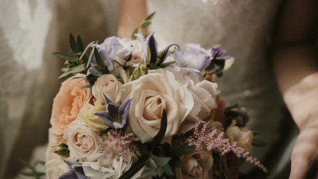 Young beautiful bride holding the wedding bouquet. Close-up view of female touching the flowers before ceremony.