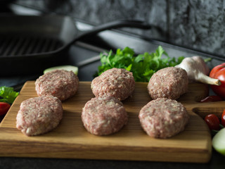 Raw homemade cutlets on a wooden board, cooked for frying. Selective focus

