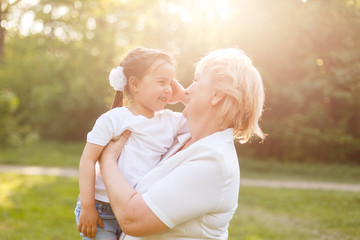 Grandmother hugging granddaughter legs and smiling.