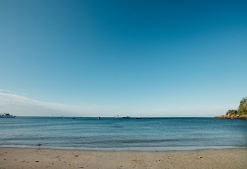 Fototapeta na wymiar Sea boats sail along shore sandy beach. Landscape sea, ships and sandy beach