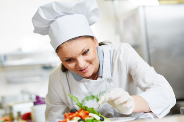 female cook chef decorating prepared salad food
