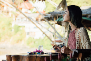 Portrait brunette woman sitting at wooden table and looking into distance