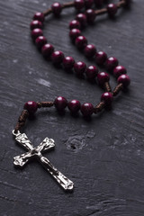 Rosary with a Christian cross on a dark wooden background.