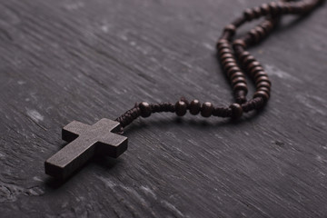 Rosary with a Christian cross on a dark wooden background.