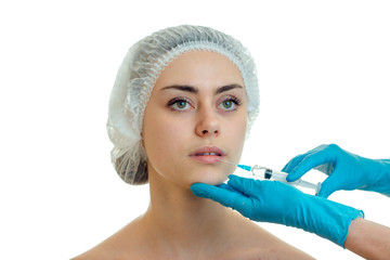 Portrait of a young girl in a medical CAP which the doctor injects the vaccine on the face with gloved hands