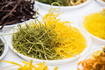 Assorted bundles of colorful raw pasta noodles.