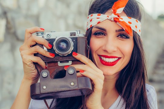 Beautiful woman taking photo with old fashioned film camera
