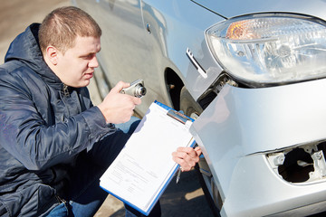 Insurance agent recording car damage on claim form