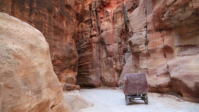 Horse-drawn carriage in Siq - narrow passage that leads to Petra, originally known to Nabataeans as Raqmu - historical and archaeological city in Hashemite Kingdom of Jordan