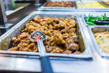 Closeup of kung pao fried chicken with sauce in buffet with spoon