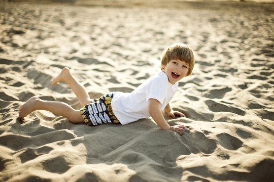 Preschool age boy playing in the sand at the beach.
