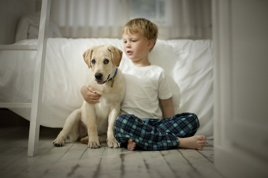Young boy sitting on floor with dog.