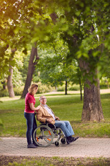 Fototapeta na wymiar elderly man in wheelchair talking with daughter in the park.
