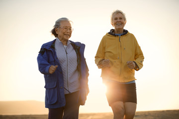 Two senior woman exercising together on the beach.