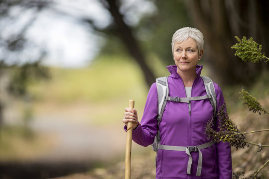 Portrait of a mature woman enjoying a peaceful hike along a forest trail.