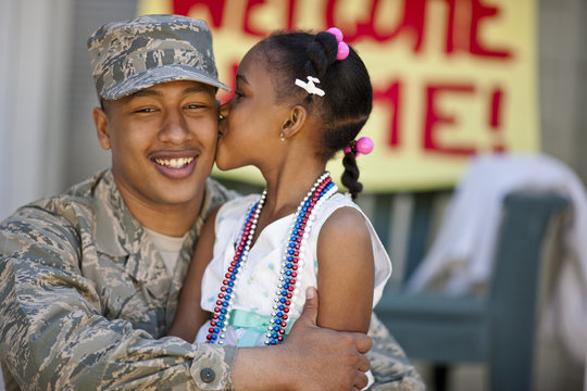 Young girl giving her father a kiss on the cheek.
