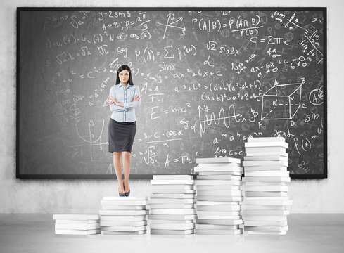 Ambitious woman and formulas on blackboard