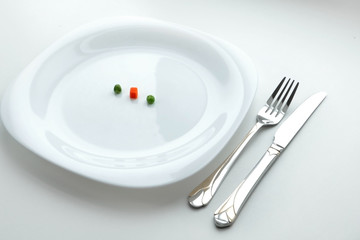 Diet dish from three peaces of vegetables on the white dish with fork and knife