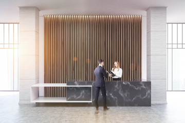 Black marble reception, wood blinds, people