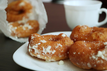 Three donuts on the white plate near tea mug