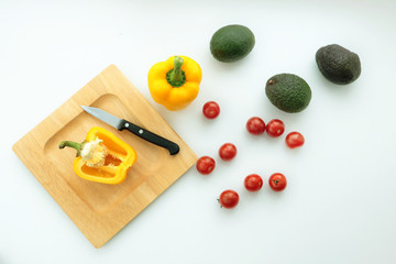 Composition of cutted paprica, avacado and tomatoes. Knife on the cutting board