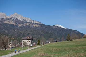 Fototapeta na wymiar Cyclists on bicycle path towards Cortina d'Ampezzo, Dolomites, Italy