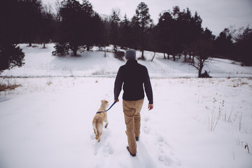 Man walks with dog in snowy field