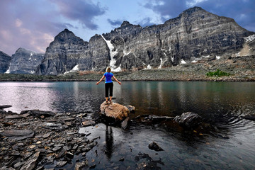 Meditation by lake in Valley of Ten Peaks.  Inner peace. Young woman meditating. Banff National Park. Eiffel lake. Wenkchemna Pass. Canadian Rocky Mountains.   Alberta. Canada.