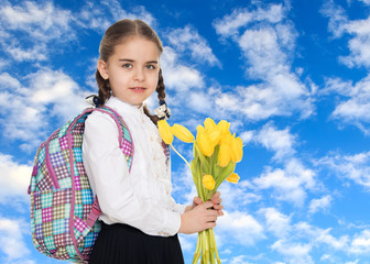 A schoolgirl with a bouquet of flowers and a backpack on her sho