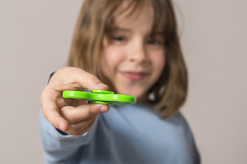 Little girl playing with green fidget spinner toy