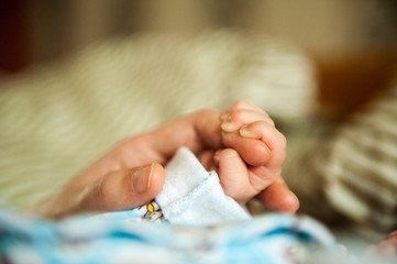 Hand the sleeping baby in the hand of mother close-up