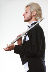 Male flutist wearing tailcoat holds flute