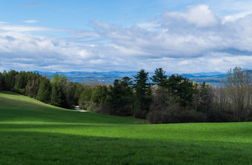Obraz premium looking across farm field in shadows to Lake Champlain, Vermont , and beyond to mountains in New York state 