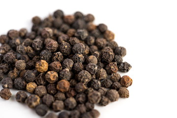 Black pepper seeds on a white background with some blurry effects (bokeh) applied. Organic seeds origin from Sarawak of Borneo, Malaysia.