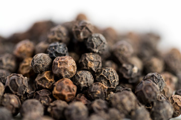 Black pepper seeds on a white background with some blurry effects (bokeh) applied. Organic seeds origin from Sarawak of Borneo, Malaysia.