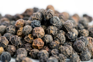 Black pepper seeds on a white background with some blurry effects (bokeh) applied. Organic seeds origin from Sarawak of Borneo, Malaysia.