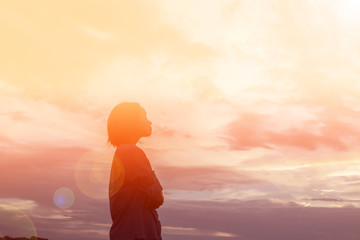 Silhouette of woman praying over beautiful sky background - obrazy, fototapety, plakaty