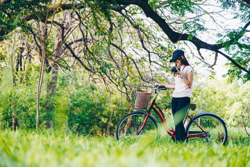 Naklejka na ściany i meble Asian young beautiful woman with red bicycle in a park.