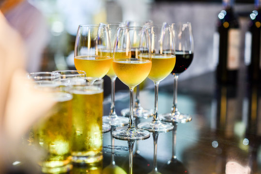 Close Up Of A Glass Of Beer, Wine And Champagne In A Bar. Many Glasses Of Different Alcohol Drink In A Row On Bar Counter