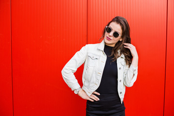 Stylish woman standing near red wall