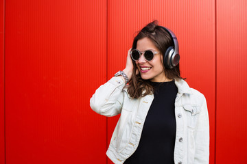 Stylish woman standing near red wall