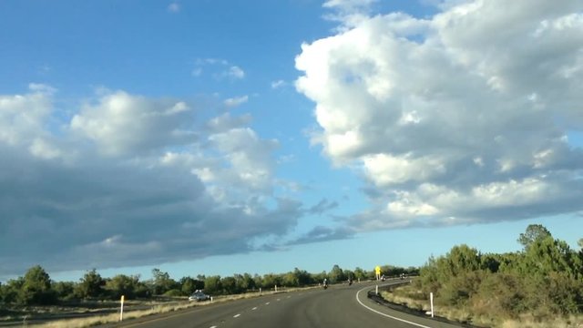HD Video of group of motorcycle riders driving through the high desert on highway 17 towards Flagstaff, blue sky with big fluffy white clouds. 2X normal speed.