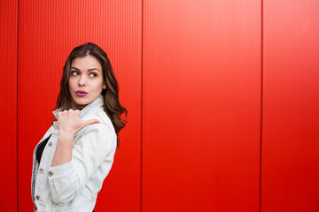 Stylish woman standing near red wall