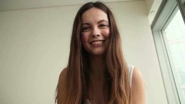 Young beautiful funny casual female making video call using electronic device web cam. Teen girl talking to friends online, blogging, waving hand, laughing in living room at home. Camera point of view