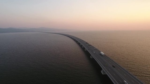 Endless road low-water bridge over Amursky gulf De-friz and Sedanka Vladivostok, Russia. Constructed for APEC summit. Modern architecture. Helicopter flight follow cars aerial. Sunset