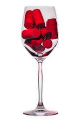 Wine glass filled with wine bottle corks illuminated by red light isolated on white background